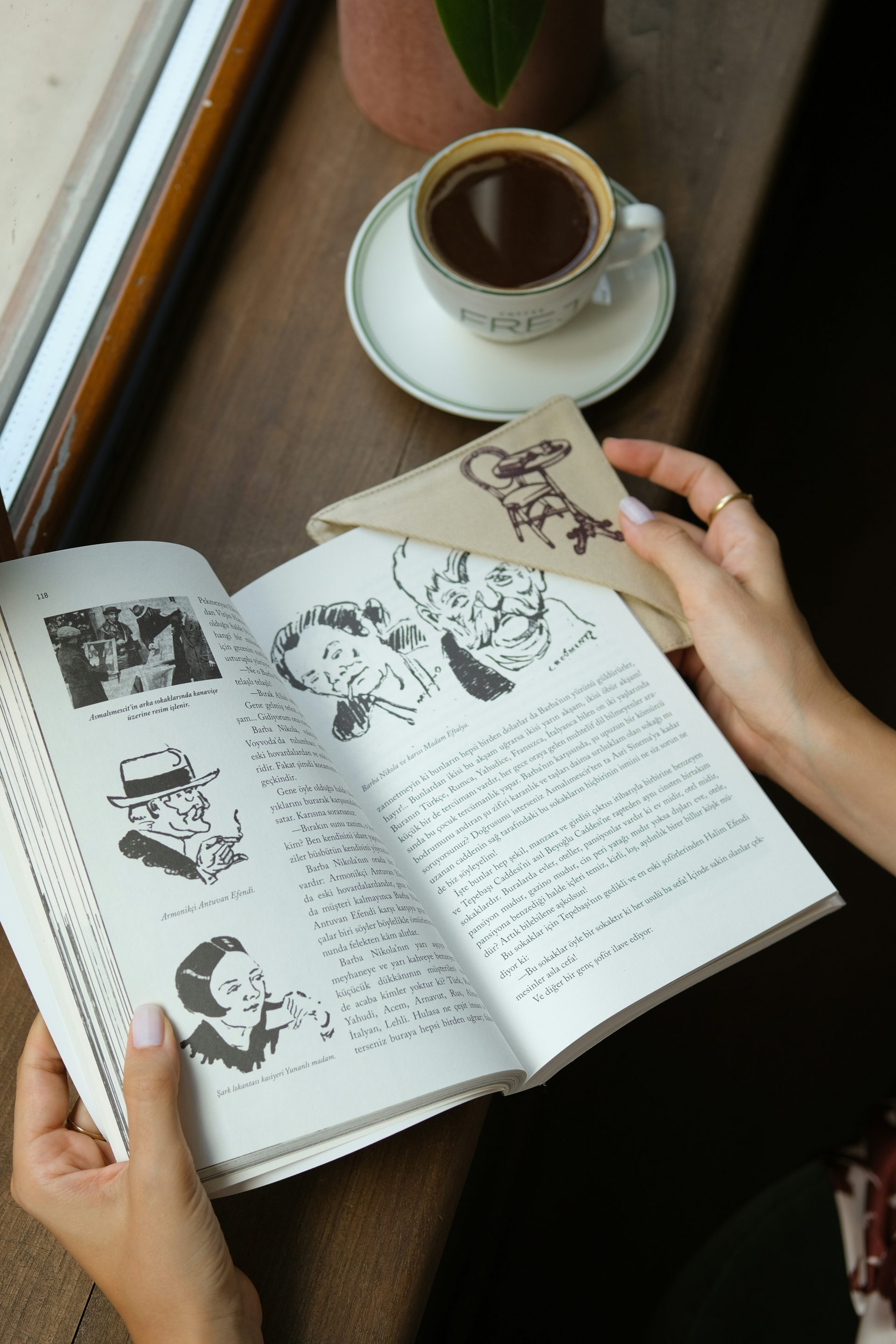 Hands holding an open book with coffee nearby